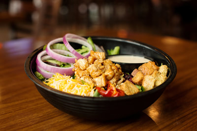 Wing Nutz salad with fresh greens, roasted tomatoes, red onions, a blend of cheeses, pine nuts, dried cranberries and croutons
